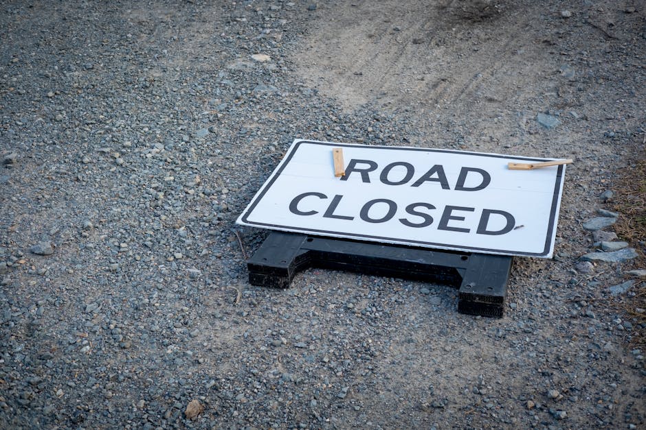 A temporary pedestrian diversion along a city street during house removals or moving activities, with a yellow sign showing a pedestrian symbol and an arrow pointing downward, positioned in the center